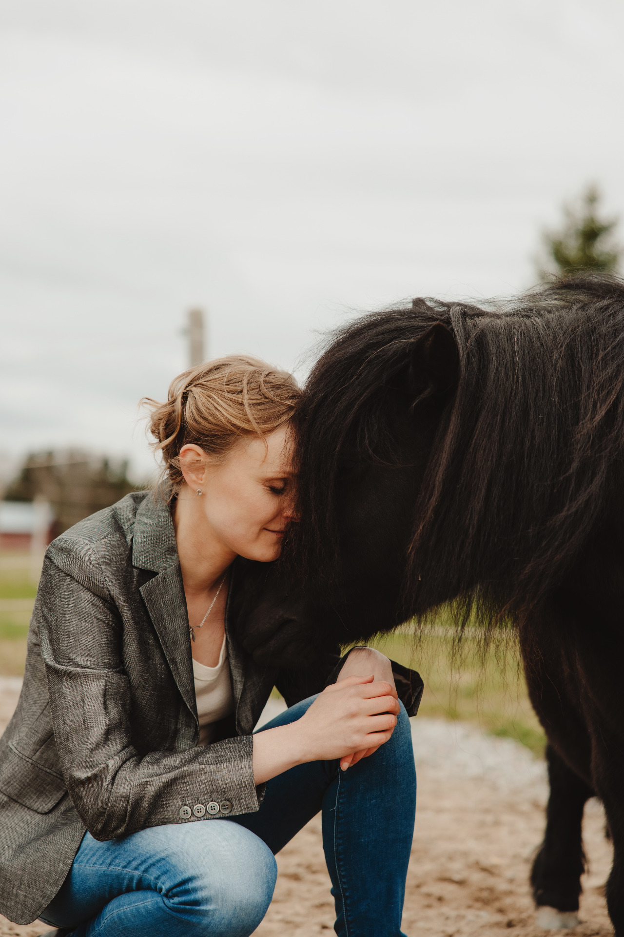 Woman and a pony are touching foreheads and having a calm moment together.